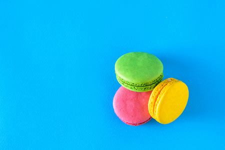 Yellow, green and red macaroons on blue background. Freshly made homemade macaroons. The view from the top. Flat lay.の写真素材