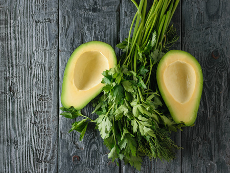 Two pitted avocado halves on a black wooden table. The view from the top. Flat lay.の写真素材