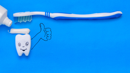 Funny tooth figurine smeared with toothpaste shows that all is well.Oral care products. The view from the top. Flat lay.の写真素材