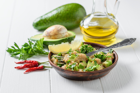 Salad of amaranth seeds, avocado and parsley with olive oil on a white wooden table. Dietary vegetarian dish.の写真素材