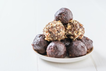 Hand-made balls of dried fruits, nuts and chocolate in a bowl on a white wooden table. Delicious...