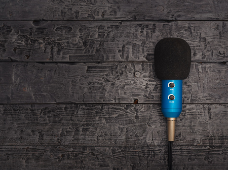 Blue microphone with wire on black wooden table. The view from the top. Equipment for conferences, music studios and meetings. Flat lay.の写真素材