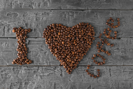 The inscription I love coffee made from roasted coffee beans on a black wooden table. The view from the top. Flat lay. Grains for the preparation of the popular drink.の写真素材