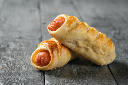 Two homemade sausages on a wooden table. Tasty meat snack made of dough and sausages.の写真素材