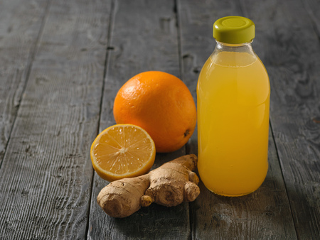Glass bottle with a drink of ginger root, lemon, orange, honey and cinnamon on a black wooden table. A remedy for the treatment of colds and strengthen the immune system.の写真素材