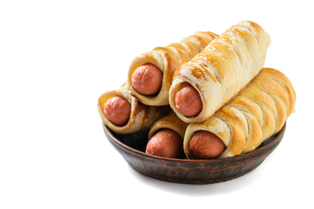 A clay bowl filled with a freshly prepared domashnii sausage rolls izolirovannye on a white background. Tasty meat snack made of dough and sausages.の写真素材
