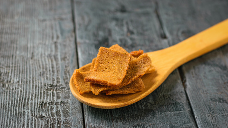 Crackers with herbs in a wooden spoon on a black wooden table. Appetizer of dry bread with spices.の写真素材