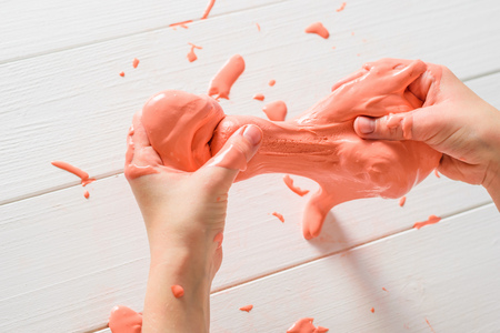 Slime is stretched and drops on a white table. Toy antistress. Toy for the development of hand motor skills.の写真素材