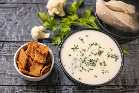 Cream of cauliflower soup and a bowl of crackers on a wooden table. Dietary cuisine for a healthy diet.の写真素材