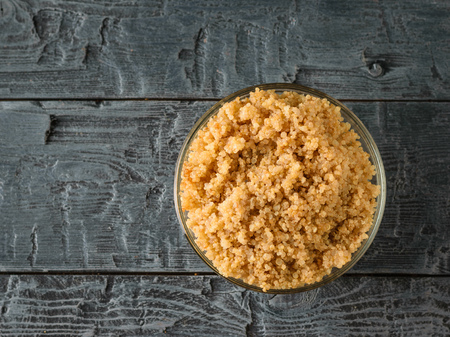 Glass bowl with boiled quinoa cereal on a black wooden table. A gluten-free boiled cereal dish. Healthy vegetarian diet. The view from the top. Flat lay.の写真素材