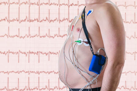A man undergoes a heart examination on the background of a red screen with a cardiogram. The method...