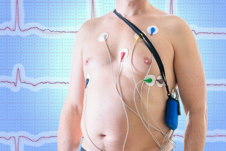Daily monitoring of a man's heart on the background of a screen with a cardiogram. The method of the halter. Method of diagnosis of heart disease.の写真素材