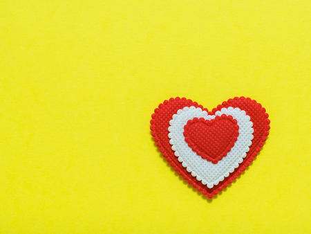 Bright red and white heart on yellow background. A symbol of love and loyalty. The view from the...