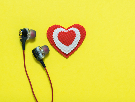 Heart of white and red colors in earphones on yellow background. Rendered image. Flat lay Toned.
