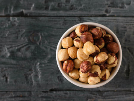 Bowl of roasted hazelnuts on a black wooden table. Prepared with the harvest of hazelnuts. The view from the top.の写真素材