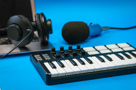 Music mixer, laptop and blue microphone with wires on blue background. Equipment for recording music...