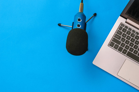 Blue microphone with laptop on blue background. The concept of workplace organization. Equipment for...