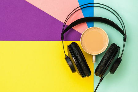 Black headphones and a Cup of coffee on a colorful background. Equipment for recording music tracks. The view from the top. Flat lay.の写真素材