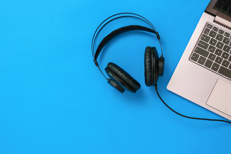 Top view of headphones connected to laptop on blue background. The concept of workplace organization. Equipment for recording, communication and listening to music. Flat lay.の写真素材