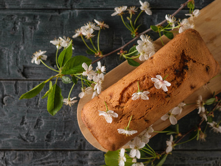Fresh homemade cake decorated with cherry flowers on a dark table. Delicious homemade cakes. The...