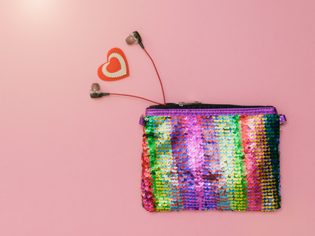 Heart and headphones sticking out of a colorful bag on a pink background. Fashion women's accessory. Flat lay. The view from the top.の写真素材