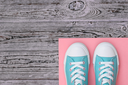 Turquoise sneakers on a pink rug on a wooden floor. Sports style. Flat lay.の写真素材