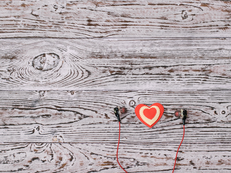 Headphones and red and white heart on wooden background. Romantic style in fashionable clothes. Flat lay. The view from the top.の写真素材