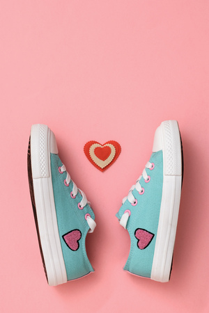 A pair of beautiful sneakers and a red and white heart on a pink background. Color trend 2019. Sports style. Flat lay. The view from the top.の写真素材