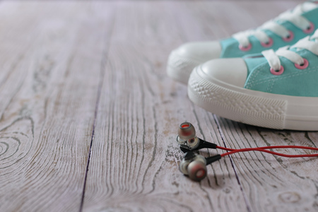 Black headphones with red wire on the floor next to turquoise sneakers. Sport style.の写真素材