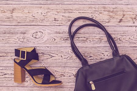 Toned image of a black women's Shoe and a black bag on a wooden background. Fashion women's accessories.の写真素材