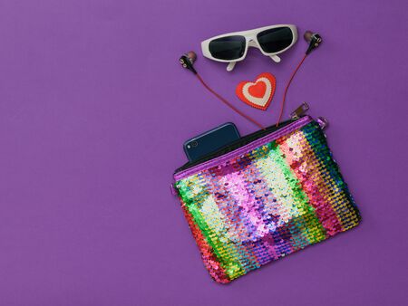 Bag the colors of the rainbow, smartphone, sunglasses and a heart on a purple background. Fashion accessories for women. Flat lay. The view from the top.の写真素材