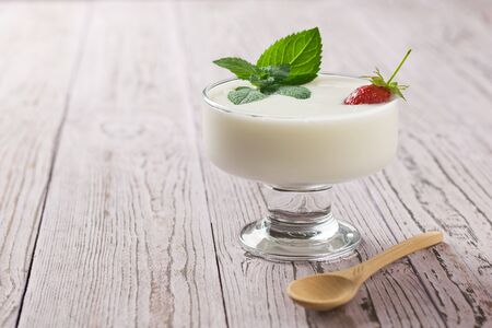 Bowl of yogurt and strawberries with mint on a wooden table. Delicious, healthy and nutritious natural food.の写真素材
