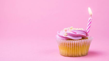 Cupcakes with berry cream and a candle on a pink background. The concept of the birthday celebration.の写真素材