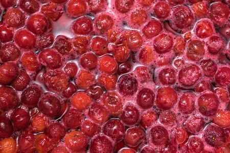 A lot of cherries cooked in sugar. Cooking homemade jam.