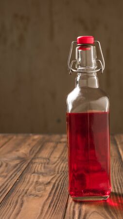 Glass bottle with plum alcohol on a wooden table. Homemade alcoholic drink made from berries plum.の写真素材