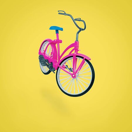 Toy red bike with a blue saddle on a yellow background. Eco-friendly mode of transport.の写真素材