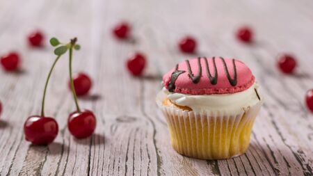 Cupcakes with berry cream decorated with chocolate on a wooden table with cherries. Dessert with fresh cherry berries.の写真素材