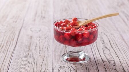 Vase with cherry jam and a wooden spoon on the table. Homemade jam from the fresh harvest of cherry berries. The view from the top. Flat lay.の写真素材
