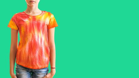 Girl in a t-shirt in the style of tie dye on a green background. White clothes painted by hand.の写真素材
