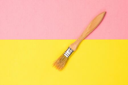Brush with wooden handle on yellow and pink paper background. Creative kit. Minimalism.の写真素材