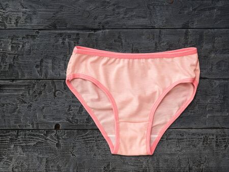 Women's pink cotton panties on black wooden background. Fashionable concept. Beautiful lingerie....