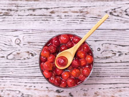 Wooden spoon in a Cup of freshly made cherry jam on a wooden background. Homemade jam from the fresh harvest of cherry berries. The view from the top. Flat lay.の写真素材