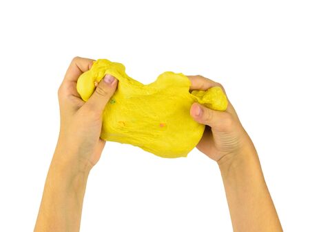 The child's arms stretch out a yellow slime isolated on a white background. Toy antistress. Toy for the development of hand motor skills.の写真素材