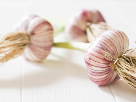 Three heads of fresh, large garlic on a white table. Healthy natural seasoning. Component of traditional medicine.の写真素材