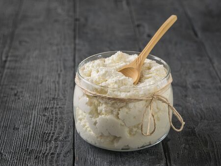 Wooden spoon in a jar with fresh cottage cheese decorated with a rope. The concept of a healthy diet.の写真素材