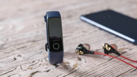 Smart bracelet blue headphones and smartphone on the pink table. Accessories to control sports. Sports style.の写真素材