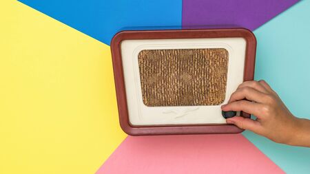 The child rotates the volume knob of the retro radio on a colored background. Radio engineering of...