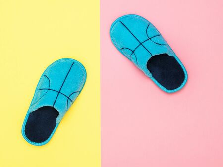 Blue house Slippers on pink and yellow background. Comfortable home shoes. Flat lay.の写真素材