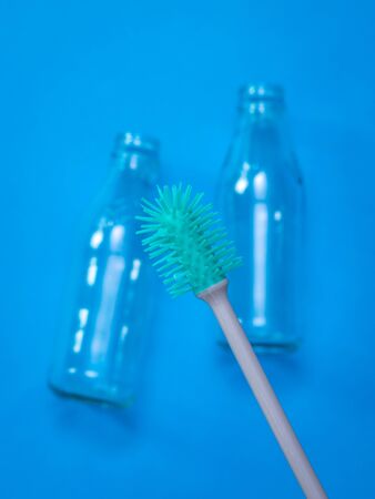Bottle washing brush and empty bottles on dark blue background. The concept of hygiene and cleanliness.の写真素材