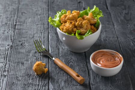 A fork of sauce and a bowl of baked cauliflower. Vegetarian cauliflower appetizer.の写真素材